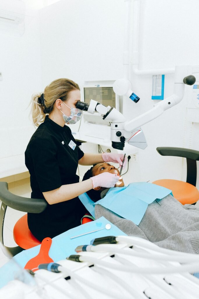 Services Female dentist in clinic examining a patient with modern dental equipment.