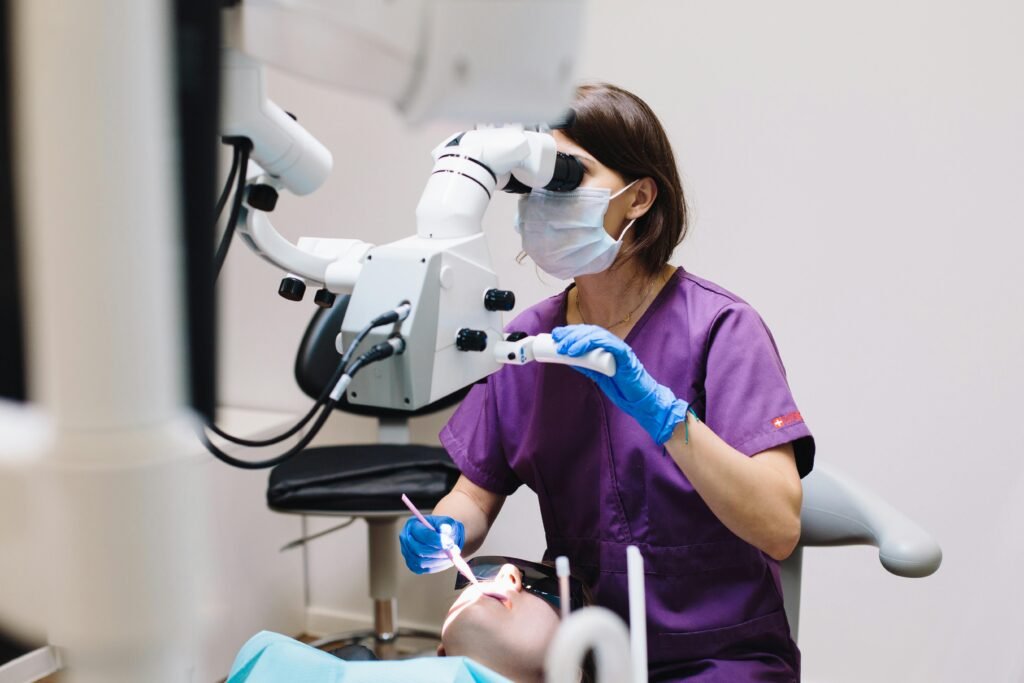 Services Female dentist using a microscope and modern technology during a patient examination in a dental clinic.
